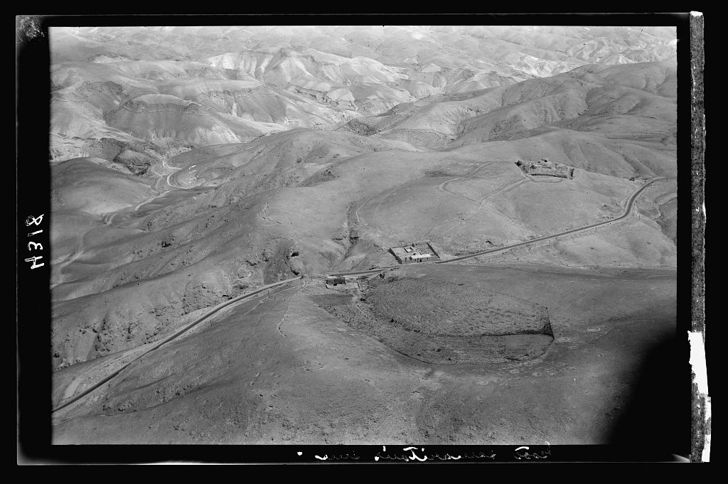 Aerial photograph from 1931 of the Good Samaritan&rsquo;s Inn beside the Jerusalem-Jericho road, with a ruined hilltop fortress behind it.