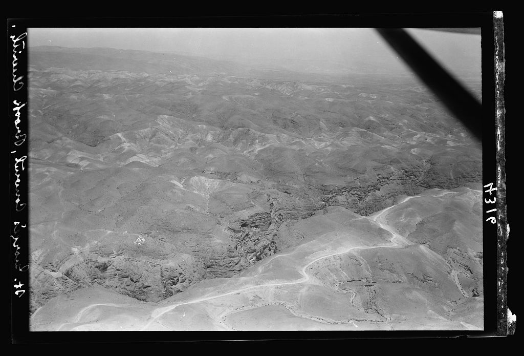 Aerial photograph from 1931 of the Wadi Qelt canyon with St George's Monastery clinging to the cliff, the Jericho road visible in the foreground.